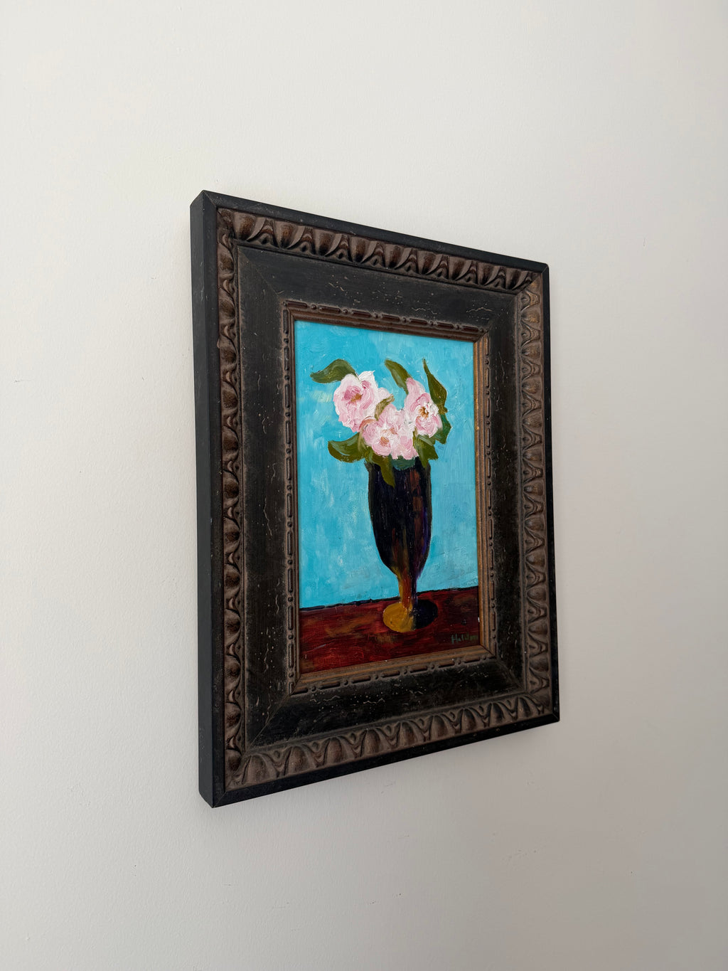 Angled view of the framed vintage floral still life displayed on a wall