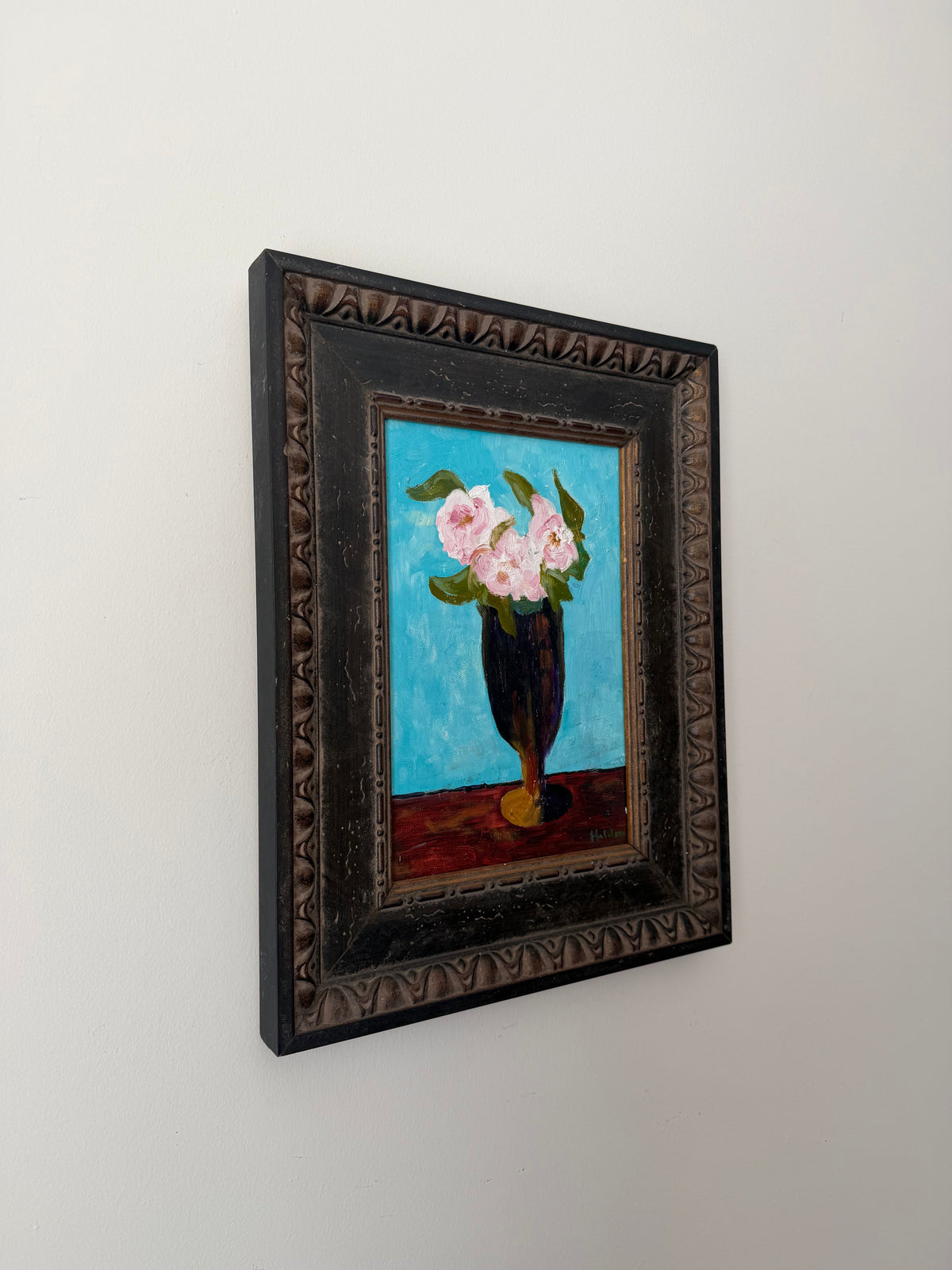 Angled view of the framed vintage floral still life displayed on a wall
